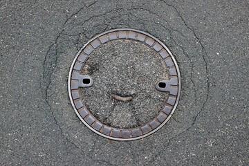 Sewer cover on a street resembling smile on a face
