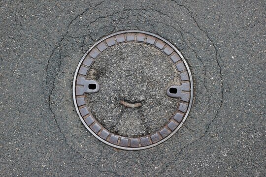 Sewer cover on a street resembling smile on a face