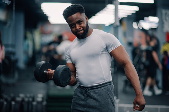 Determined bodybuilder lifting dumbbell in modern gym