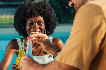Couple sharing colorful drinks by the pool on summer vacation