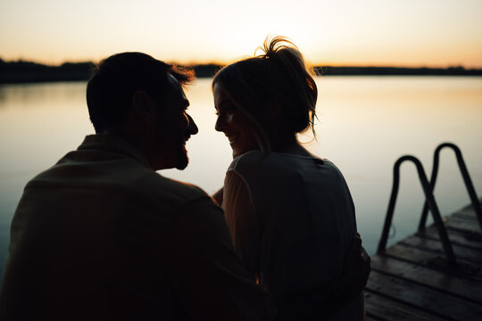 Romantic couple sharing intimate moment at sunset on lake pier