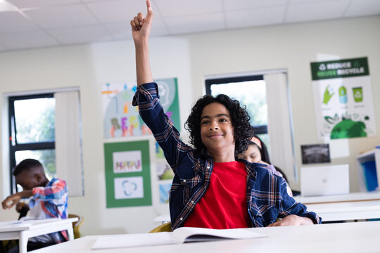 In classroom, enthusiastic boy raising hand, eager to participate in lesson, at school