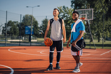 Obraz premium Two male basketball players relaxing after training outdoors on sunny summer day