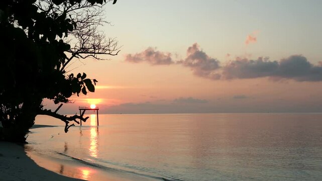 Dramatic clouds reflect the last light of the day on a serene beach in Maalhos, Maldives.