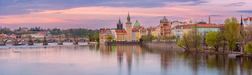 Panoramic view of Charles Bridge and Vltava River in Prague Czech Republic at sunrise with historic buildings and pink sky