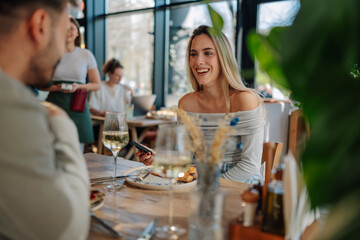 Smiling woman using smartphone while having lunch with man in restaurant