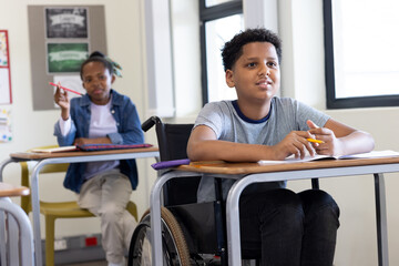 Diverse students in classroom engaged in learning, boy in wheelchair participating, at school