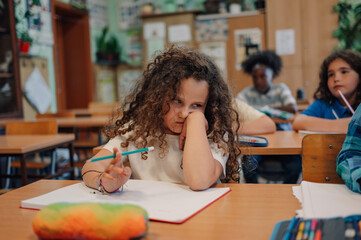 Bored elementary school student struggling with schoolwork in classroom