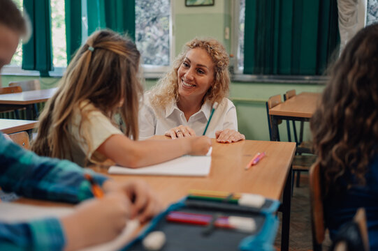 Teacher helping young girl with her studies in classroom
