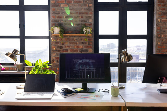 Modern office desk with computer screen displaying code and business charts