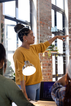 woman presenting coding ideas on glass board in modern office