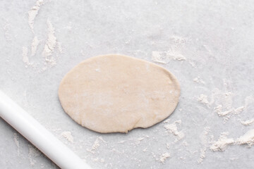 Overhead view of rolled out paratha dough, top view of flaky flatbread dough, process of making paratha