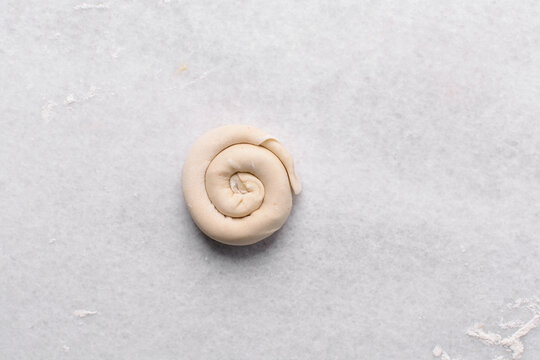 Overhead view of rolled paratha dough on a marble countertop, top view of flaky flatbread dough, process of making paratha