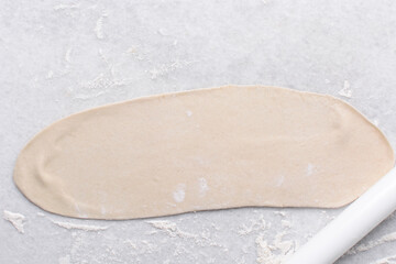 Overhead view of rolled out paratha dough, top view of flaky flatbread dough, process of making paratha