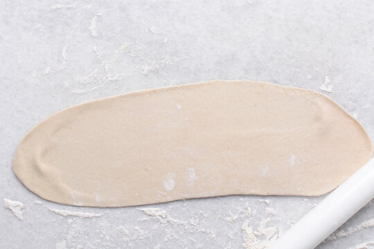 Overhead view of rolled out paratha dough, top view of flaky flatbread dough, process of making paratha