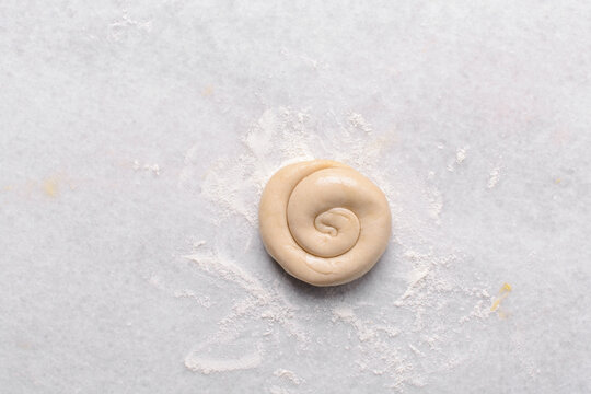 Overhead view of rolled paratha dough on a marble countertop, top view of flaky flatbread dough, process of making paratha