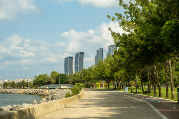 Modern Waterfront Promenade and Park in Istanbul Turkey with Walking Path Along Coastline and Skyscrapers Skyline Under Cloudy Sky on Sunny Day