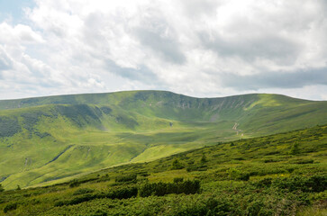 Picturesque view of lush green valleys and mountains stretching under a majestic cloudy sky, evoking serenity and a connection with nature. Carpathian Mountains, Ukraine