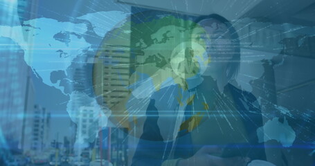 Interacting mid adult businesswoman touching holographic globe in corporate office, with smartphone