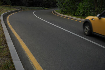 Obraz premium yellow mini car enters a sharp turn during early autumn dusk, emphasizing the importance of careful driving and caution on the road to prevent accidents. fast speedy dangerous moving 