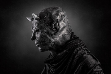 Portrait of a bad devil with horns on head over dark misty background