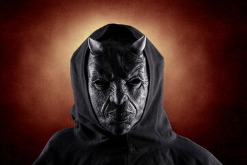 Portrait of a bad devil with horns on head over dark fiery background