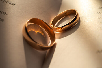 Golden wedding rings on an open book, symbolizing eternal love, unity, and commitment. Romantic sunlight adds warmth and emotion to this elegant close-up