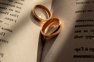 Golden wedding rings on an open book, symbolizing eternal love, unity, and commitment. Romantic sunlight adds warmth and emotion to this elegant close-up