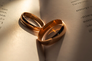 Golden wedding rings on an open book, symbolizing eternal love, unity, and commitment. Romantic sunlight adds warmth and emotion to this elegant close-up