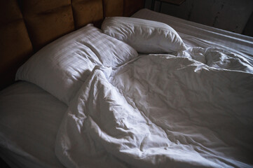 Unmade bed in soft natural light, cozy and inviting, showing rumpled white sheets and pillows in a peaceful bedroom interior, symbolizing rest, intimacy, and comfort