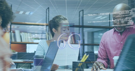 Reviewing woman typing from printed docs on laptop at office desk, with holographic 6G overlay