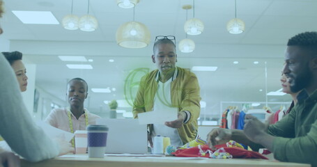 Collaborating team reviewing design sketches, fabric swatches in design studio with measuring tape