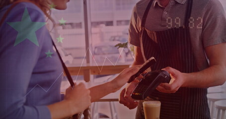 Tapping smartphone customer in blue top paying with handheld terminal at wooden counter with latte
