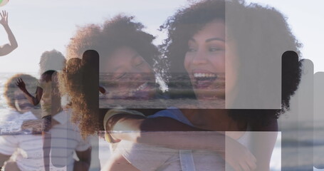 Hugging man and woman wearing casual summer clothes at sandy beach, with children waving at water