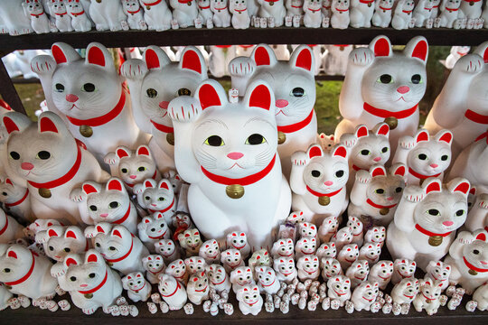 Statues of white maneki neko beckoning cats at Gotokuji temple in Japan
