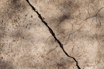 Large diagonal crack on old concrete surface, cracked mossy cement floor