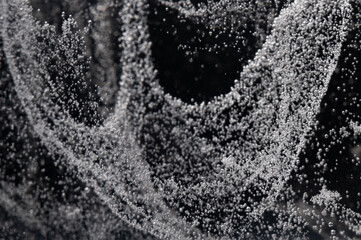 Close-up view of bubbles rising in liquid during a dynamic movement in a dark environment