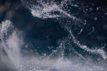 Swirling droplets create mesmerizing patterns in water on a dark background