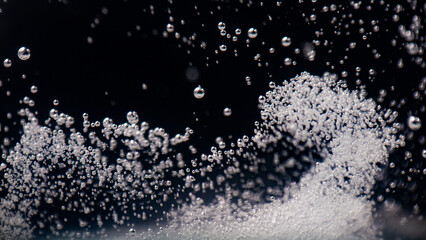 Close-up view of bubbles rising in liquid during a dynamic movement in a dark environment