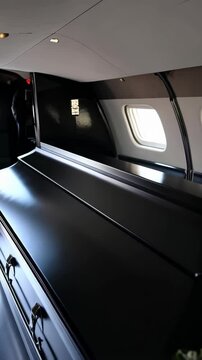 View of a polished black casket with roses inside a private jet for final journey, conveying respect and commemoration.