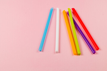 Colorful drinking straws arranged on a pink background