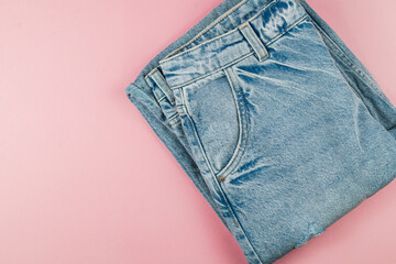 Folded denim jeans on a pastel surface