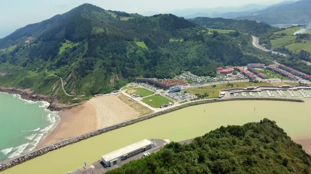 Aerial perspective captures the serene beauty of orio, showcasing its beach, harbor, and lush green hills