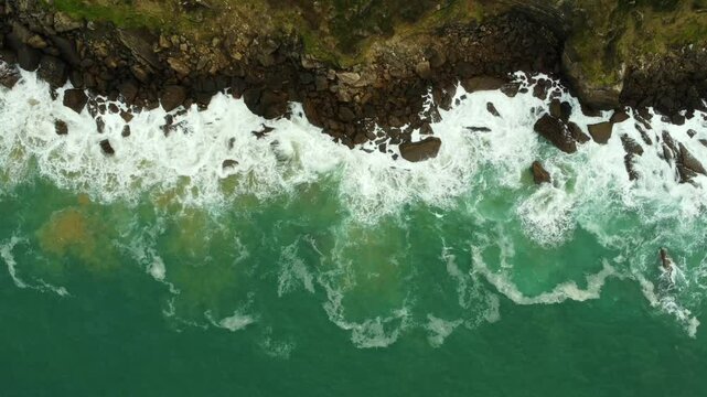 Aerial view of waves crashing against the rocky coastline of zarautz, gipuzkoa, in the basque country during summer