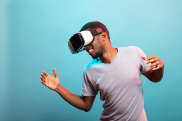 African american guy wearing a virtual reality headset, enjoying an immersive digital experience against an isolated background. Young man with VR goggles interacting with an augmented reality.