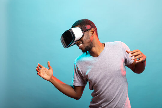 African american guy wearing a virtual reality headset, enjoying an immersive digital experience against an isolated background. Young man with VR goggles interacting with an augmented reality.