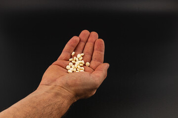 Hand holding white pills against a dark background