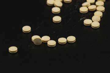 Yellow tablets scattered on a black surface in a clinical setting