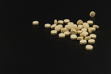 Yellow tablets scattered on a black surface for a study