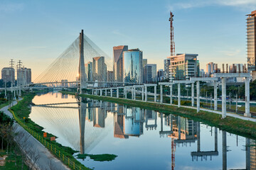 Urban cityscape with a cable-stayed bridge, modern buildings, and the Pinheiros River in the city of São Paulo.